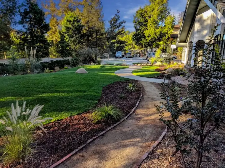 Well-maintained garden path curving through lush green lawn and colorful landscaping.