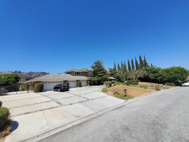 Modern suburban home with a spacious driveway and landscaped yard on a clear, sunny day.