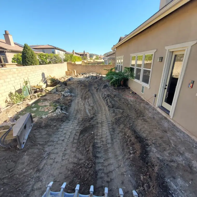 Cleared backyard with dirt path and construction materials, ready for landscaping.