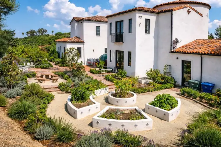 Modern white house with terraced garden and native plants in a sunny outdoor setting.