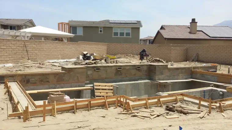 Construction site with a foundation and framework for a residential swimming pool.