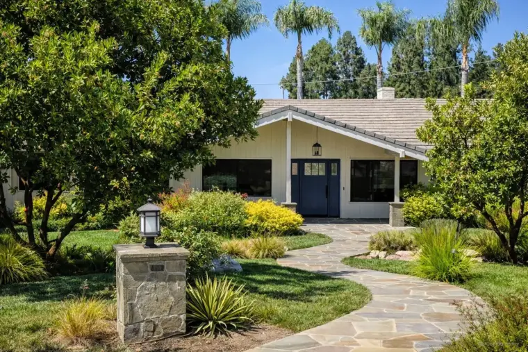 Charming suburban home with landscaped garden and stone pathway under clear blue sky.