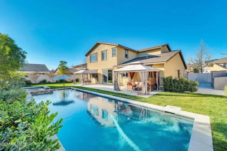 Luxury home with pool and cabanas in a sunny backyard setting. Perfect for outdoor relaxation.