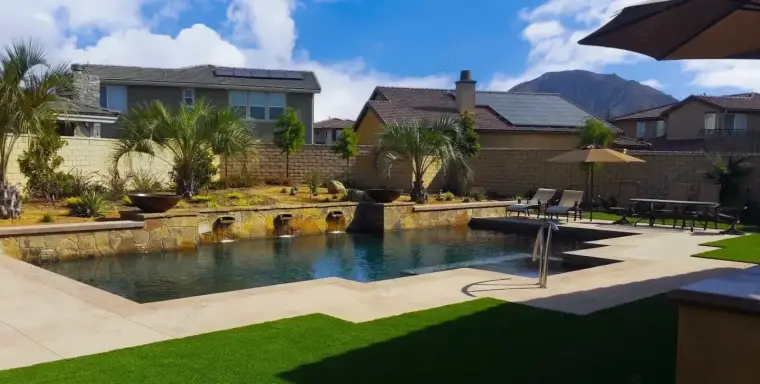 Luxurious backyard pool with palm trees and mountain views under a clear blue sky.