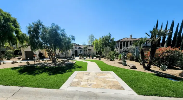 Lush garden paths lead to a beautiful Mediterranean-style home with diverse landscaping.