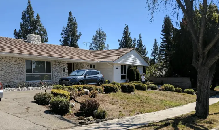 Single-story house with stone accents and landscaped yard on a sunny day.