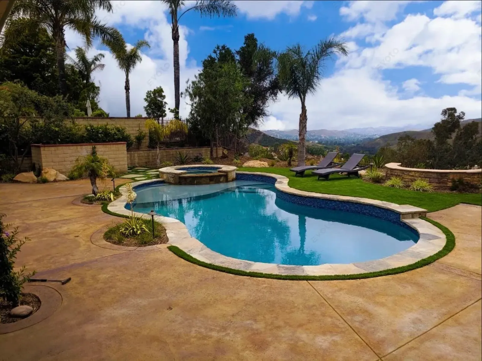 Scenic backyard pool with lush landscaping and mountain views under a blue sky.